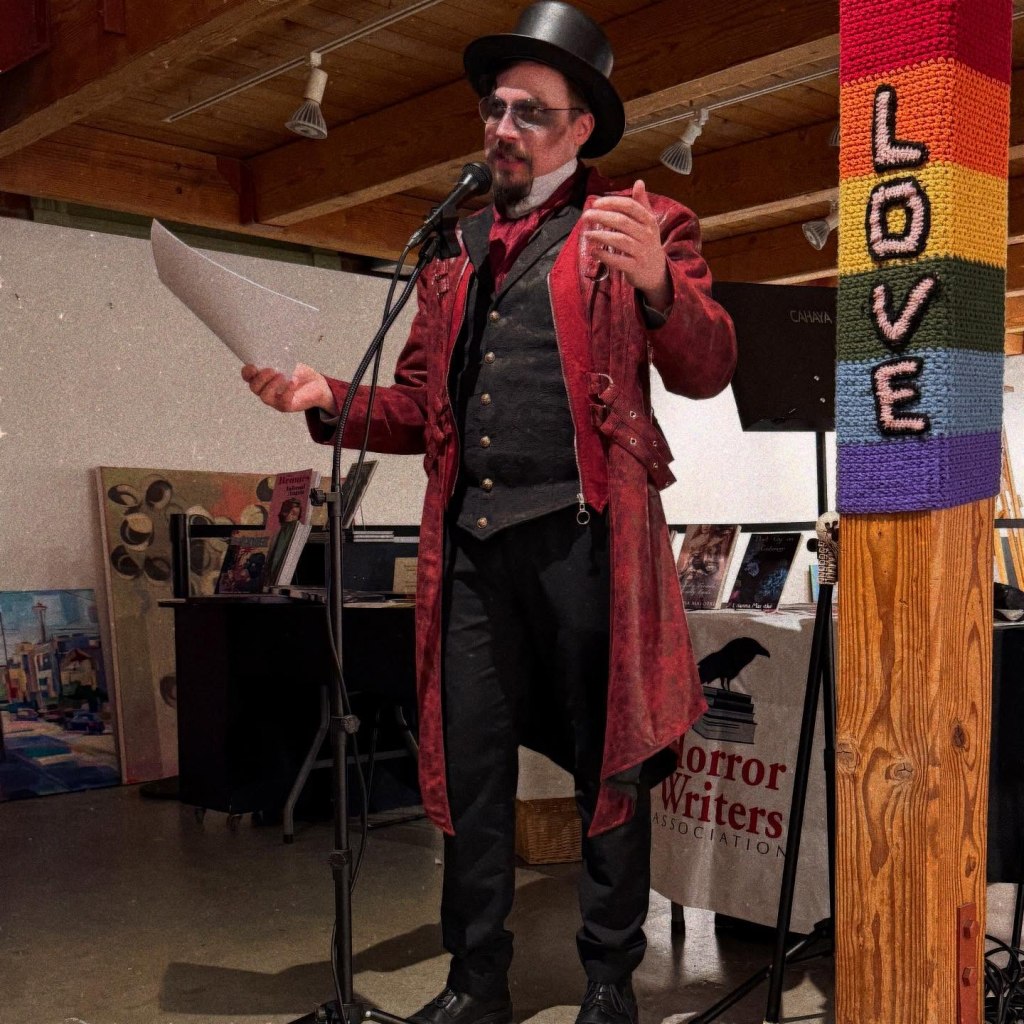 A man in a top hat stands in front of a microphone next to a pillar with a sign that says "Love"