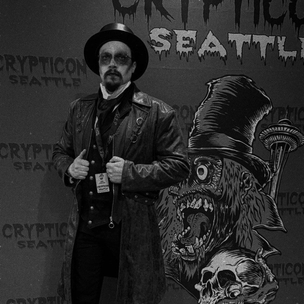 Crypticon Seattle photo with a person in a tophat in front of the sign.